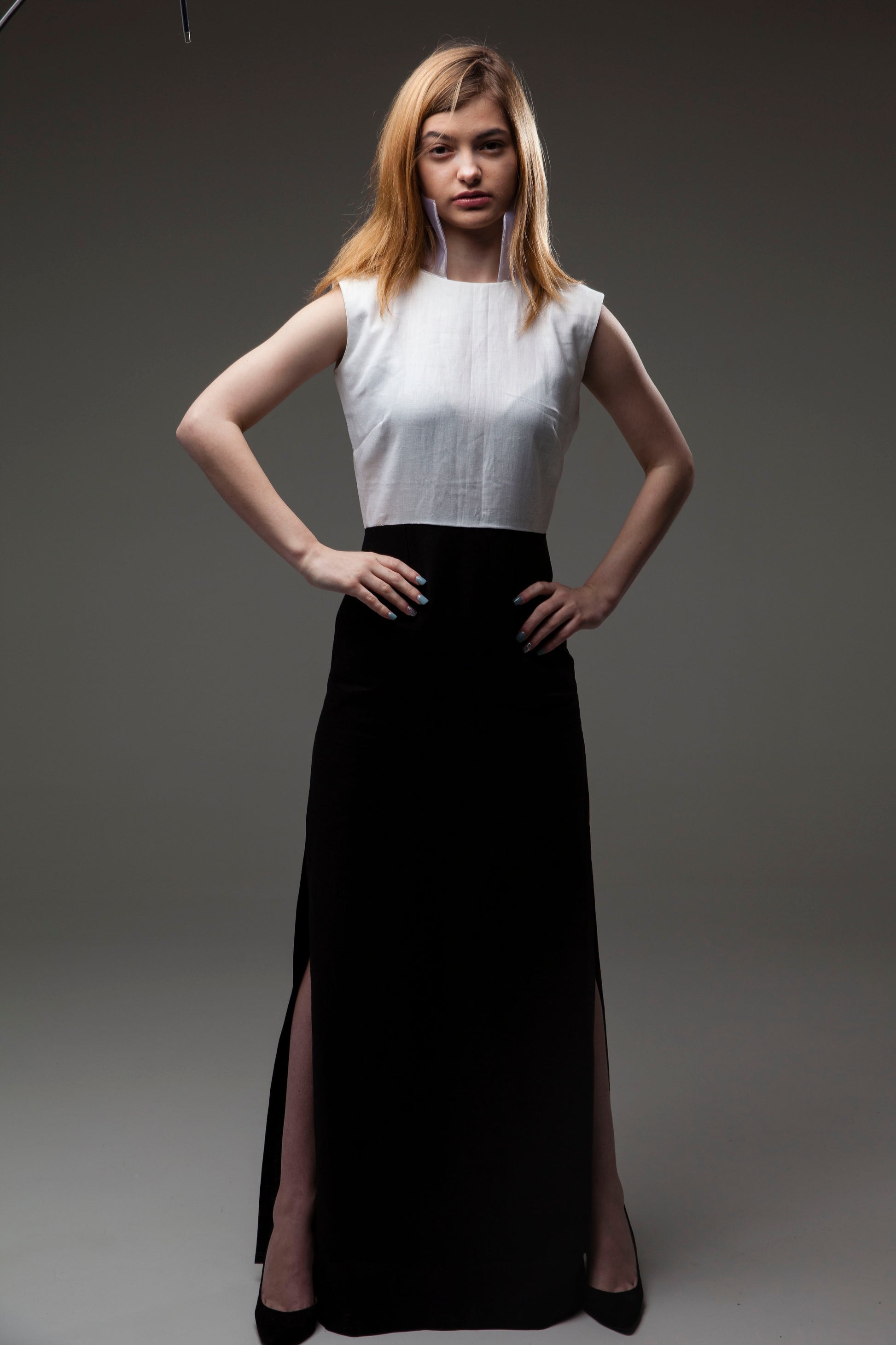 Anastasi Fashion design – The Queen Dress (Front): A woman standing, wearing a black and white spring dress with an organza collar.